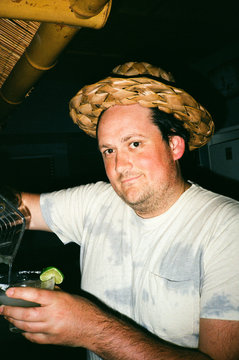 male with straw hat pouring cocktail