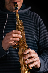 Naklejka premium soprano saxophone in the hands of a guy on a black background