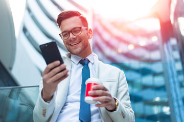 Happy business man reading sms on smart phone