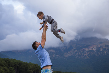 Father holding up little son in the air playing together family lifestyle daddy and child walking outdoor parenthood concept day holiday © Maria