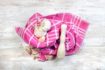 WOODEN MORTAR WITH GARLIC ON KITCHEN CLOTH AND WOOD BACKGROUND