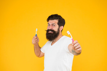 Brush teeth. Fresh breathe. Mint paste. Healthy teeth. On guard of freshness. Teeth whitening procedure. Bearded man holds toothbrushes yellow background. Hipster happy smiling face cares hygiene