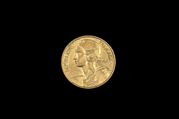 An old five French centimes coin, shot close up in macro, on a black background