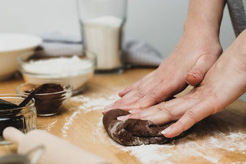 Woman hands kneading chocolate dough, cooking cookies or dessert. Cooking at home.