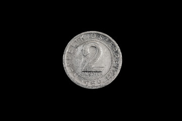 A close up, macro image of a silver, Austrian two pfennig coin isolated on a solid black background