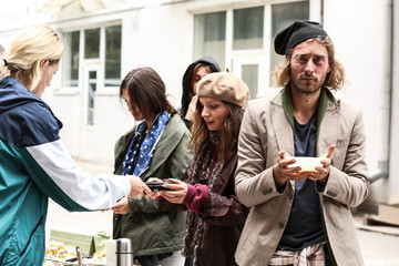 Volunteers giving food to homeless people outdoors