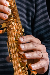 soprano saxophone in the hands of a guy on a black background