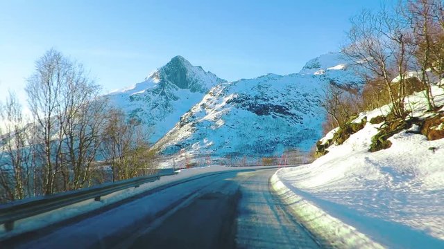 Mountain road covered in snow in a northern country in winter filmed from a moving car.