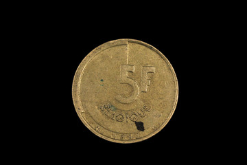 An old, gold five Belgian franc coin, shot close up in macro, agianst a black background
