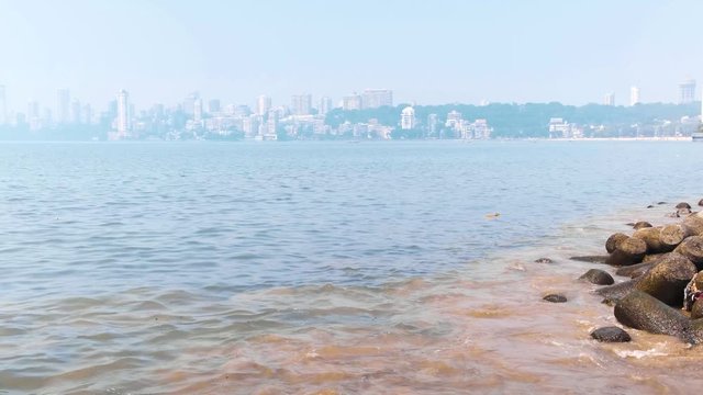 High tide in the Arabian sea, waves crashing at shore, Mumbai downtown at the horizon.