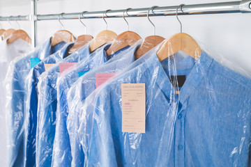 Rack with clothes in modern dry-cleaner's, closeup