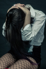 imitation of an old film of a color image with grain and toning. A photo of a brunette sitting on a chair with her head in her hands. The concept of depression