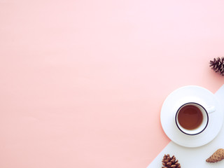 Cup of tea isolated on a peach color background surrounded by cones.