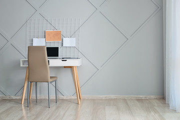 Stylish workplace with laptop near grey wall