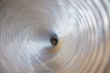 Optical illusion of photo. Futuristic plastic pipe inside iridescent swirling spiral. Bright...