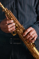 soprano saxophone in the hands of a guy on a black background