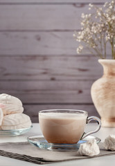 Cup of hot latte coffee with marshmallows on a white table
