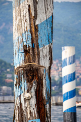 Close view of an old weathered wooden blue and white painted post, bollard in Lake Como, Lombardy, Italy, selective focus