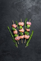 Raw chicken shish kebab with broccoli,  Barbecue. Black background. Top view. Space for text