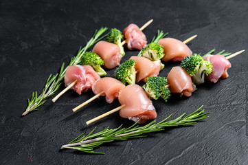 Raw chicken shish kebab with broccoli,  Barbecue. Black background. Top view