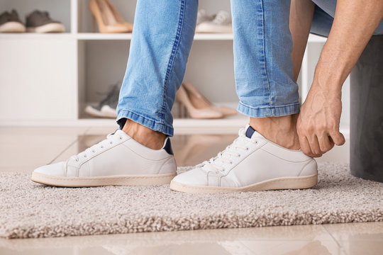 Young Man Putting On Shoes At Home