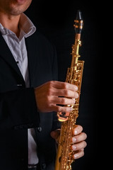 soprano saxophone in the hands of a guy on a black background