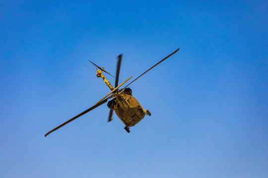 A photograph from the ground of a combat helicopter in a desert area training. Military helicopter performing search and rescue training exercises.