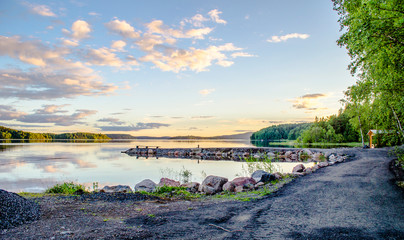 Beautiful sunset with reflection in water. Mirror summer lake. Lake Ladoga Karelia. Russia
