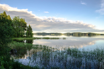 Reflections of a cloudy sky on a lake. Mirror summer lake. Ladoga Lake in Karelia. Russia