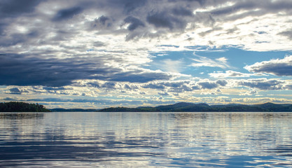 Beautiful sky and its reflection on the lake. Mirror summer lake. Ladoga Lake in Karelia. Russia