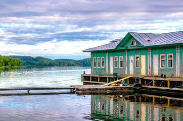 Beautiful sunset with reflection in the water on Ladoga Lake. Mirror summer lake with an old house. Karelia, Russia