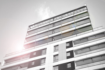 Detail of modern residential flat apartment building exterior. Fragment of new luxury house and home complex. Glass surface with sunlight. Black and white.