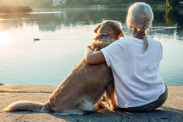 Blonde girl with dog from the back , lake view .