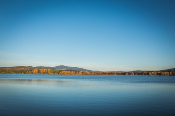 The Lipno Dam - Cerna v Posumavi, Czech Republic in a bright summer day. The lake is calm, has clean blue water. There are no clouds in the sky.