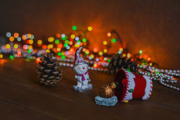 New Year's card - a bucket with gifts on a wooden background, a multi-colored garland and a snowman figurine. New Year and Christmas gifts.