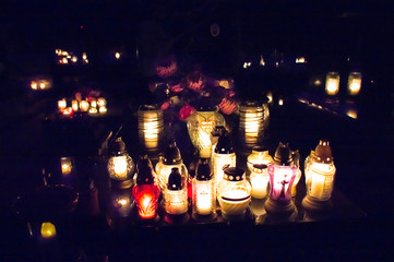 Monument and candles in the cemetery. All Saints Day in Poland. Candles in the cemetery. All candles in the dark.
