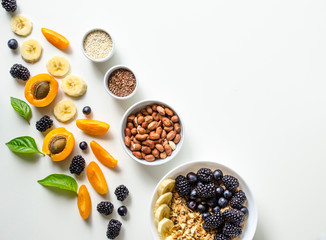 Creative layout of fresh summer fruits, muesli, nuts and grains on a white background with space for text. 