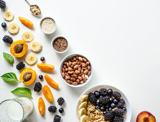 Creative layout of fresh summer fruits, muesli, nuts and grains on a white background with space for text. 