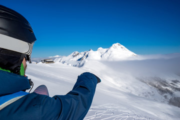 Fototapeta na wymiar Snowboarder freerider points to the snow field to descend from the top of Caucasus mountains in winter resort of Krasnaya Polyana