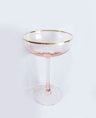 Large vintage pink champagne glass with gold rim on a white background