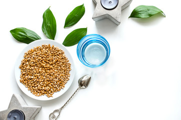 Sprouts of wheat on a plate with water and candles on a white background and with space for text. Healthy food. Useful breakfast. View from above.