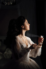 Female beauty. Lovely woman at home. Bride spray perfume stylish woman wearing a white dress spray...