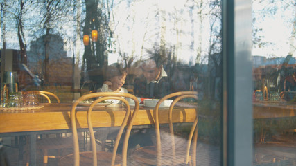 Outside the window son and father in cafe