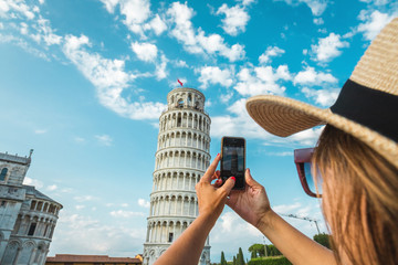 Tourist girl in Pisa, Italy. Woman photographing with mobile cell phone the historical monument