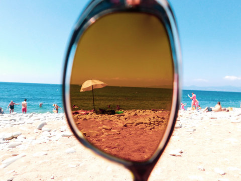 vue fun sur la plage au travers d'un verre de lunette de soleil en &eacute;t&eacute;