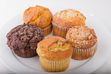 Assortment of freshly baked muffins on a white plate with isolated background