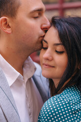 the man closed his eyes and kisses the woman in the head. closeu