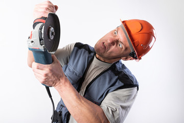Builder with angle grinder, in a helmet, with a funny expression on his face.