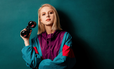 Style woman in 90s punk clothes with binoculars on aqua menthe color background