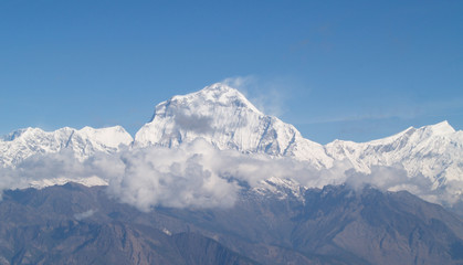 Amazing autumn panorama with mountains covered with snow and forest against the background of blue sky and clouds. Mount Everest, Nepal.